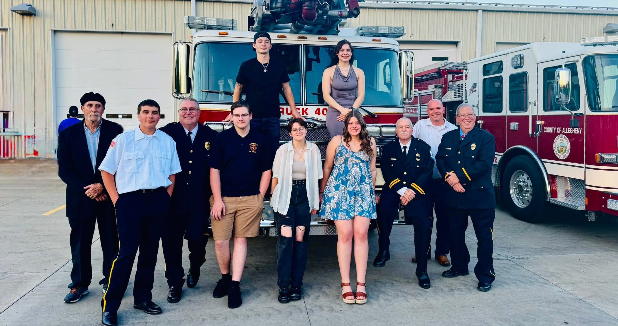 Students graduating the Fire Academy pose in front of a fire engine
