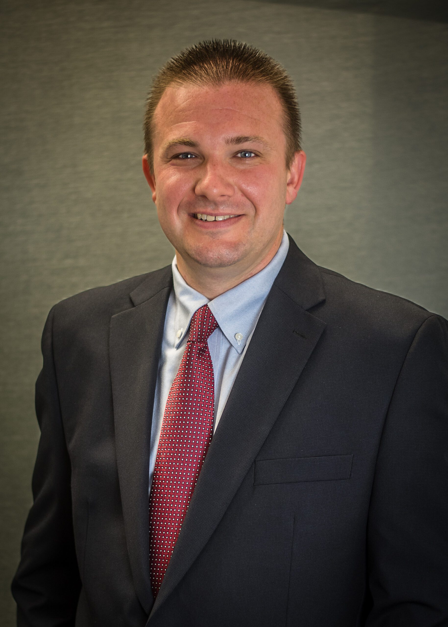 Dr. O'Black smiles in a suit and red tie.