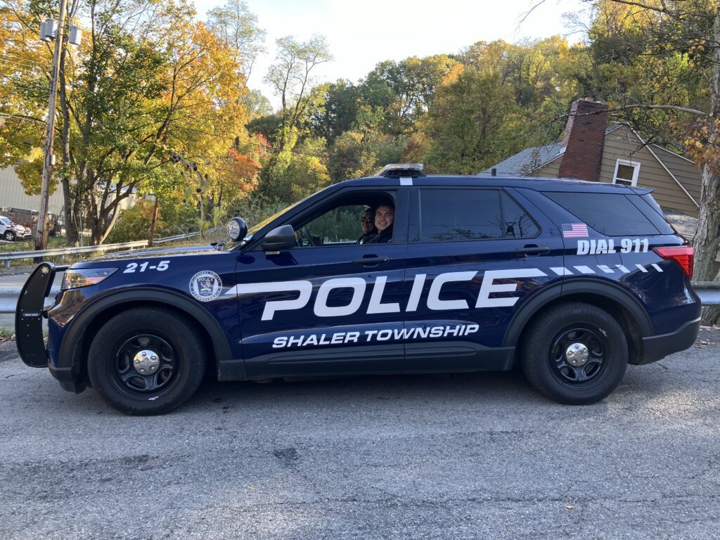 Two officers smile from the front seats of a Shaler Twp Police cruiser