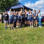 Student athletes and coaches stand outside at the Invitational