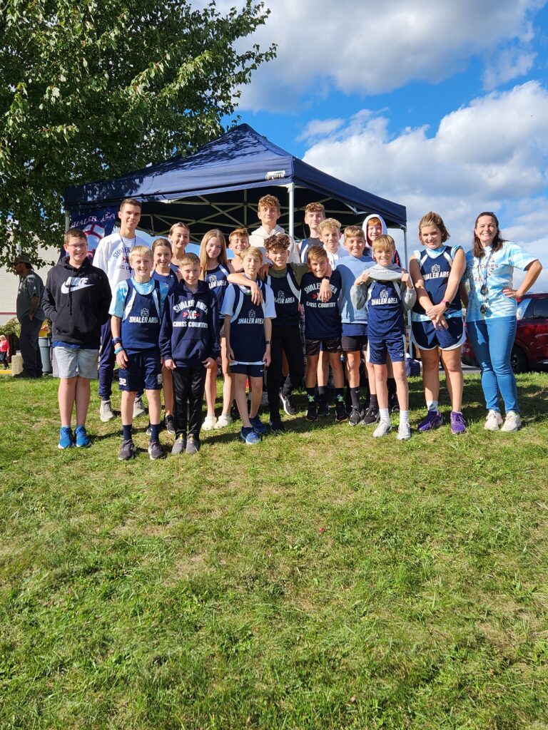 Student athletes and coaches stand outside at the Invitational