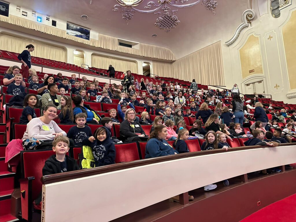 Students smile in the red velvet seats of Heinz Hall