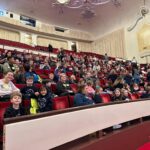 Students smile in the red velvet seats of Heinz Hall