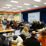 Dr. O'Black addresses the cafeteria full of community members