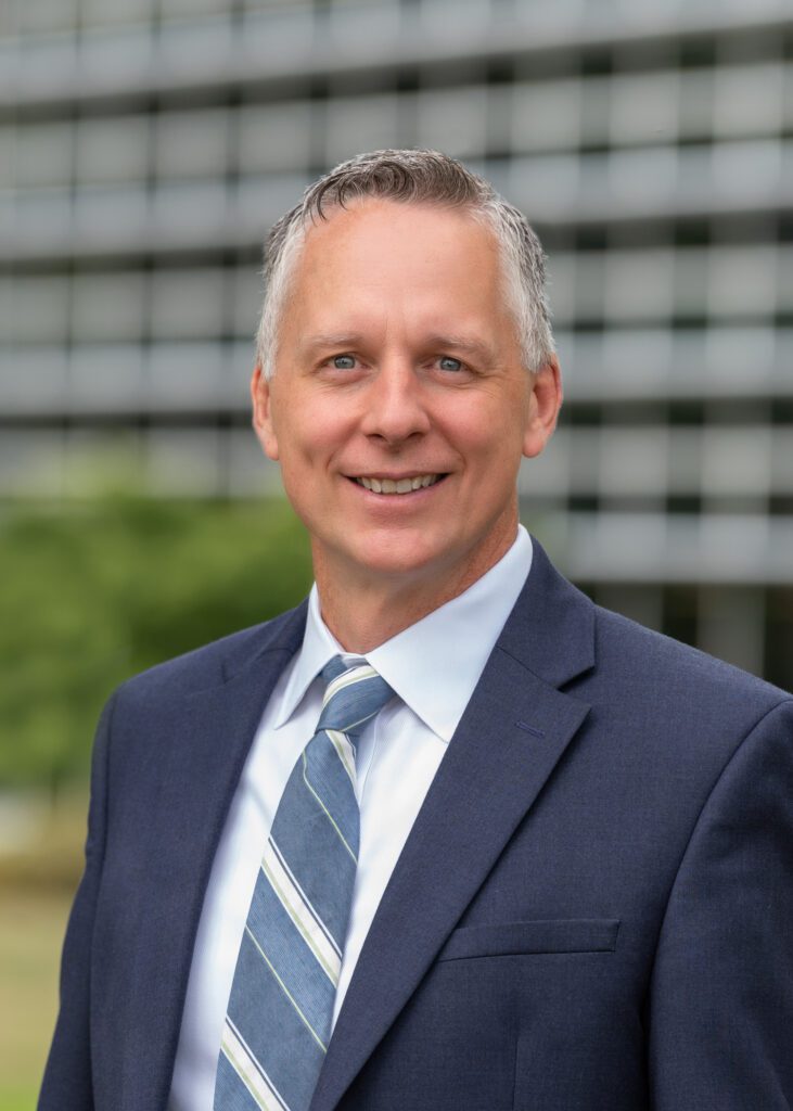 Dr. Reed smiles in front of the campus