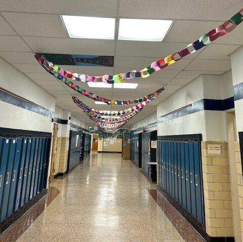 A banner emblazoned with "be the reason somebody smiles" hangs in the hallway as a paperchain can be seen zig zagging down the ceiling