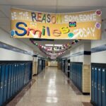 A banner emblazoned with "be the reason somebody smiles" hangs in the hallway as a paperchain can be seen zig zagging down the ceiling