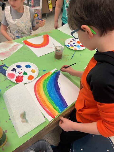 student paints a rainbow