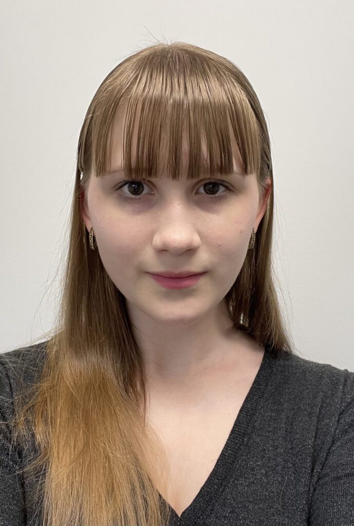 Anna, with brown hair, looks at the camera